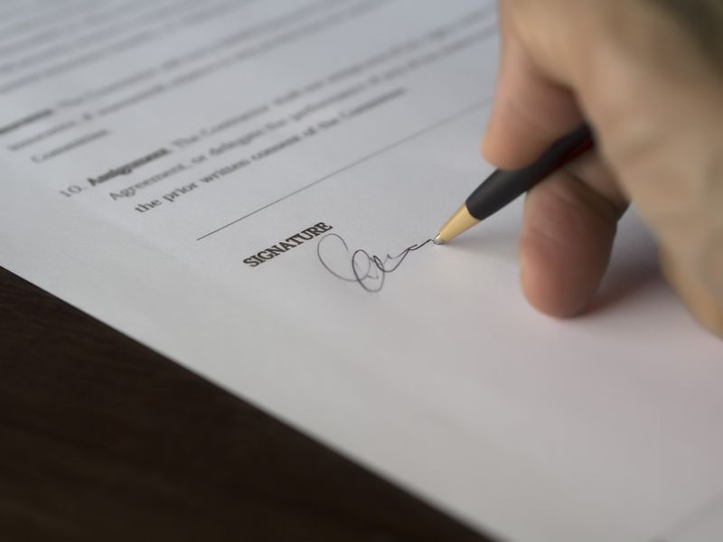 Hand signing a sale agreement on the signature line